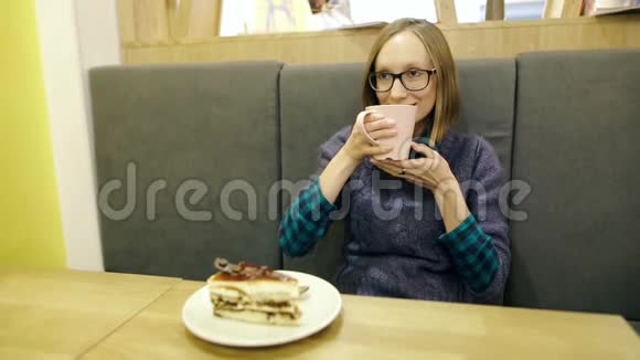 戴着眼镜的梦中少女喝着带有蓝莓和薄荷的斯堪的纳维亚热茶在粉红色的杯子里放松视频的预览图