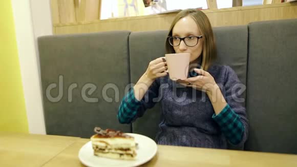 戴眼镜的快乐女孩喝着红茶喝着蓝莓和薄荷从一个粉红色的大杯子里拿出来在咖啡馆里放松视频的预览图