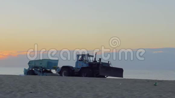 清晨一辆带拖车的大型推土机在沙滩上清扫沙子视频的预览图