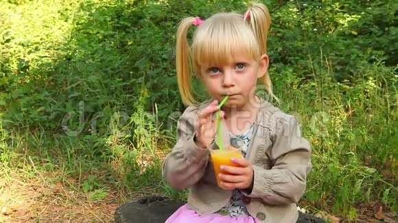 美丽的小女孩在户外喝橙汁视频的预览图