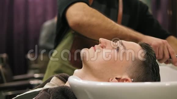 在一家理发店里一位年轻人用一个面目全非的理发师给他洗头视频的预览图