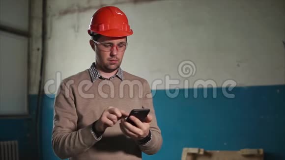 那人手里拿着一部电话戴着一顶防护头盔系在工程师头上视频的预览图