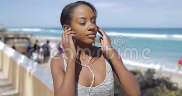 在海边戴耳机和运动服的少数民族妇女视频的预览图