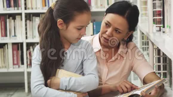 漂亮快乐的成熟女人在给她的小女儿读一本书视频的预览图