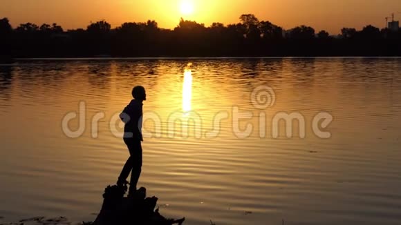 太阳落山时一个激动的人在湖岸上举起两只手视频的预览图