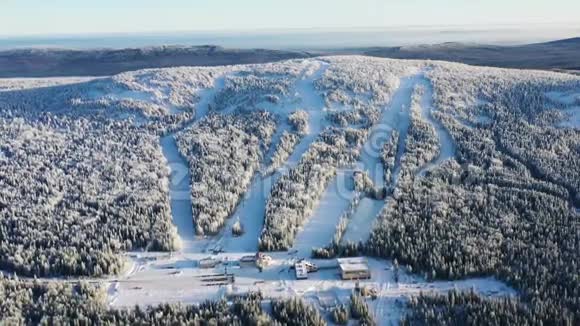 观看现代滑雪基地和滑雪道周围的森林在冬季与蓝天录像空中景观视频的预览图