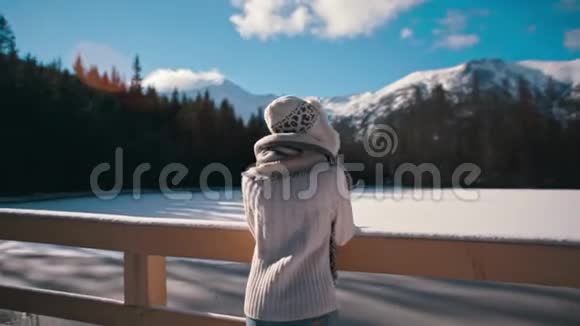 瘦小的少妇看着冬天的山湖带着太阳的光辉视频的预览图