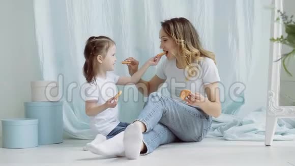 妈妈和小女孩互相喂饼干一个有个小女儿的女人坐在地板上视频的预览图