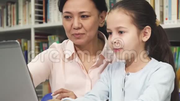 快乐的母亲和女儿在学习时使用笔记本电脑视频的预览图