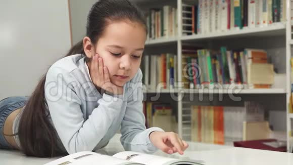 一个美丽快乐的亚洲小女孩微笑着享受着阅读这本书视频的预览图