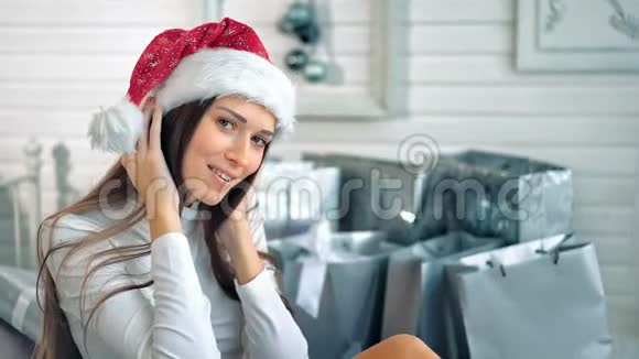 戴着圣诞帽的漂亮女人在白色的房间里摆姿势视频的预览图