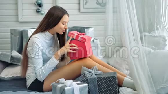 可爱的微笑的年轻女性在白色房间里打开礼物视频的预览图