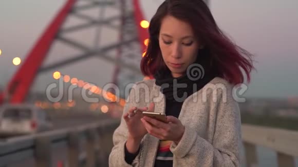 年轻漂亮的女孩晚上在城里用智能手机视频的预览图