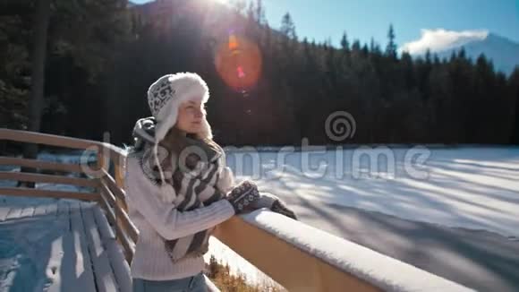瘦小的女人看着冬天的山湖有着太阳的光辉视频的预览图