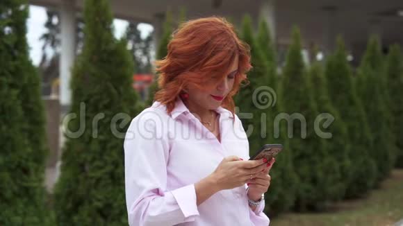 一个红头发的漂亮女人的肖像一个女人正在她的手机上读一条信息视频的预览图