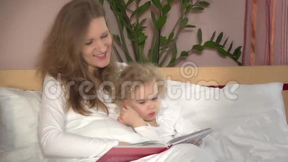 女人和宝贝女孩看书妈妈和她床上的小可爱视频的预览图