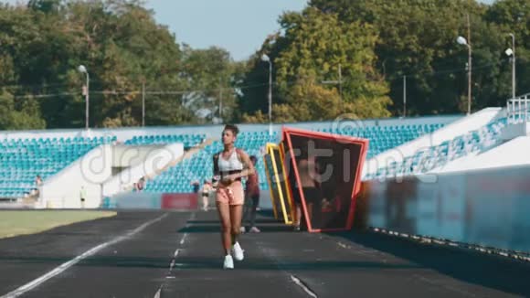 女跑步者把受伤的腿按在跑道上视频的预览图