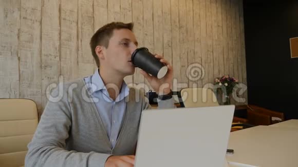 Officelife概念年轻的上班族坐在电脑旁集思广益用4k拍摄的纸杯喝咖啡视频的预览图