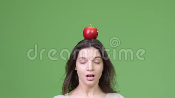 近距离拍摄一个头上戴苹果的年轻美女视频的预览图