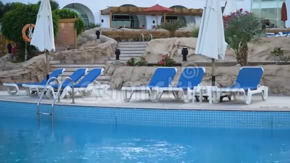 在阳光明媚的豪华度假胜地豪华的空酒店海滩上有漂亮的白色日光浴床躺椅和遮阳篷视频的预览图