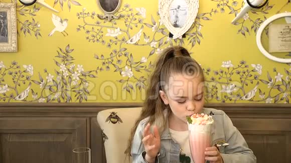美丽的小女孩喝奶昔鸡尾酒的肖像上面有棉花糖舔她的嘴唇奶油里的嘴唇全额视频的预览图