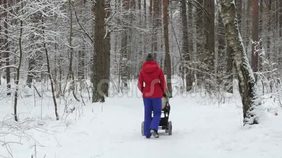 妈妈带着婴儿车在冬天的森林里做母亲视频的预览图