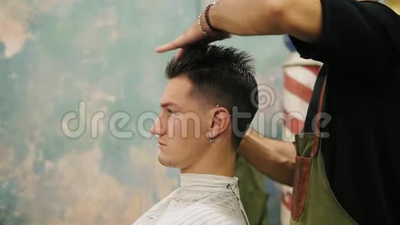年轻英俊的白种人侧视他的耳朵上有穿孔头发被一个复古时尚的理发师吹干视频的预览图