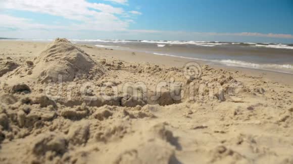 阳光沙滩上的孤沙堡城堡金字塔特写视频的预览图
