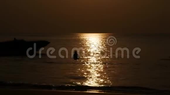 人们在海滩上散步和日落时在海里游泳的剪影假期概念特写镜头4k视频的预览图