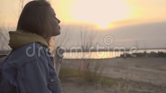夕阳西下秋天的海滩和悲伤的女孩坐在树上视频的预览图