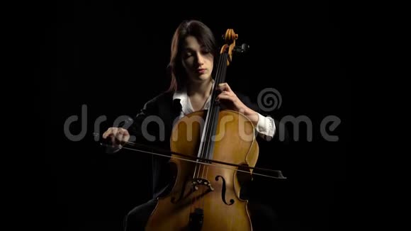 女人在黑暗工作室演奏大提琴黑色背景视频的预览图