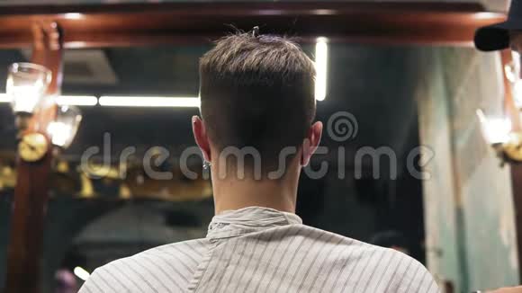 一个年轻人坐在理发店的椅子上剪了头发理发师剪了客户的头发视频的预览图