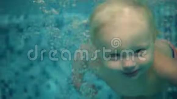 可爱的金发幼儿正在游泳池的水下潜水在那里游泳直到他的母亲帮助他获得视频的预览图