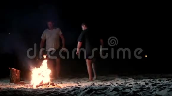 晚上人们在海滩上跳过篝火视频的预览图