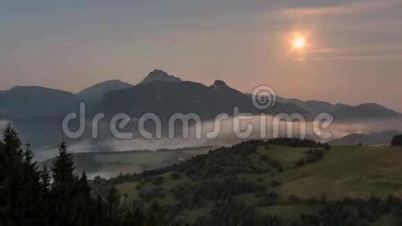 在雾蒙蒙的群山中日出时月亮落下了黎明视频的预览图