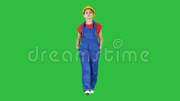 年轻的女工程师带着黄色的安全帽走在绿色的屏幕上Chroma键视频的预览图