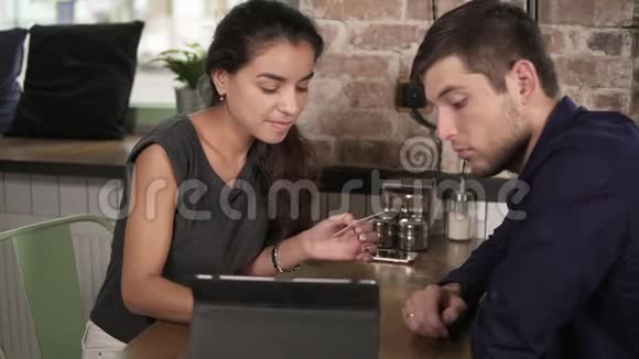 浪漫的年轻夫妇使用平板电脑和支付信用卡坐在平板电脑在咖啡店快乐的女人视频的预览图