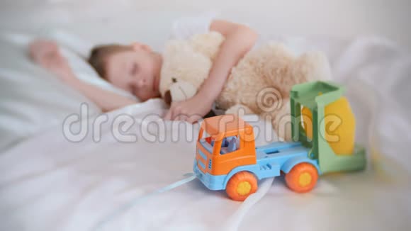 七岁的男孩和他的玩具熊和塑料汽车睡觉专注于玩具车视频的预览图