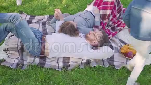 躺在草地上的父母孩子们在公园里玩得很开心也有跑步的背景视频的预览图
