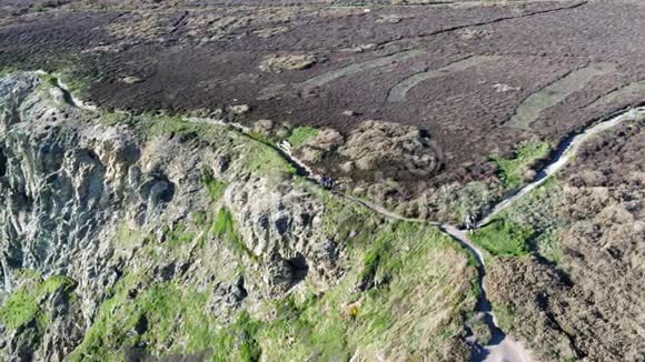 在安格列西威尔士历史悠久的南斯塔克灯塔附近的美丽悬崖上散步的人的鸟瞰图视频的预览图