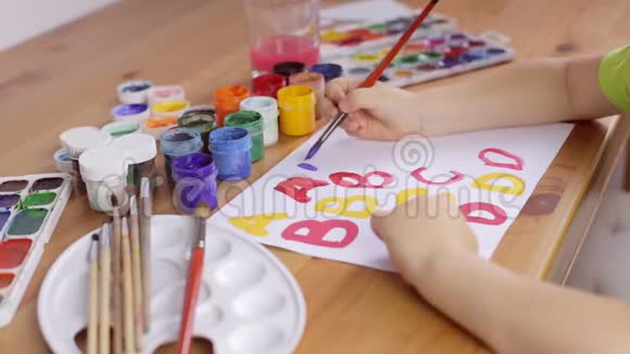 小孩用画笔在白纸上写字母视频的预览图