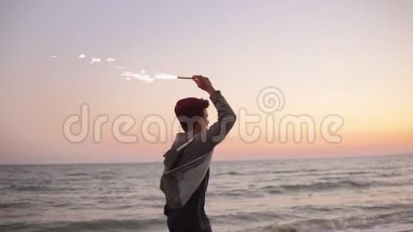 日落时分年轻英俊的非洲男人在海边奔跑手里拿着燃烧的闪闪发光的蜡烛慢动作视频的预览图