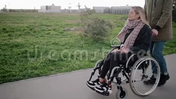男子与残疾妇女在轮椅上行走视频的预览图