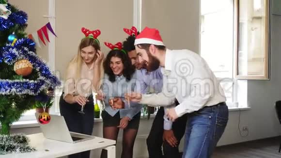圣诞帽快乐团队的侧面景观在公司里做电话会议用起泡葡萄酒碰杯视频的预览图