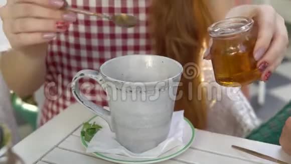 喝茶女人把蜂蜜倒进一杯茶里视频的预览图