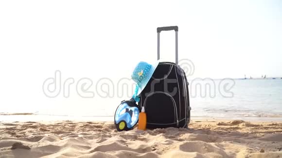 在美丽的海滩上带着奶油草帽和潜水面具的旅行假日旅行箱旅游广告视频的预览图