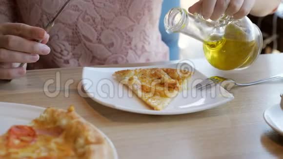 咖啡馆里的年轻女子正在吃比萨饼倒着橄榄油视频的预览图