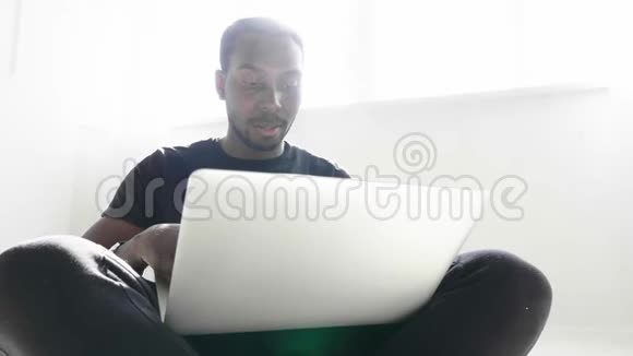 穿休闲服装的英俊的美国黑人商人正在使用电脑视频的预览图