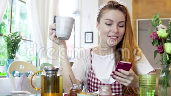 女人边喝茶边用手机微笑视频的预览图