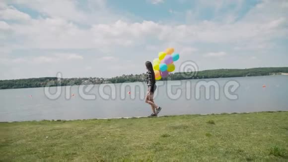 美丽的女孩带着五颜六色的气球走在河湾上看着水视频的预览图